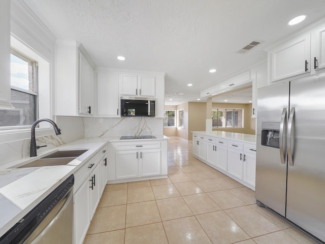 kitchen with sink, white cabinets, a textured ceiling, light tile patterned floors, and appliances with stainless steel finishes