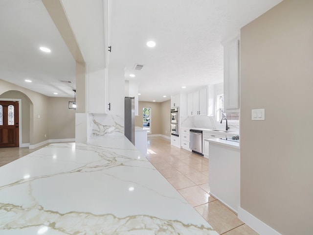 kitchen with decorative backsplash, light stone counters, sink, dishwasher, and white cabinets