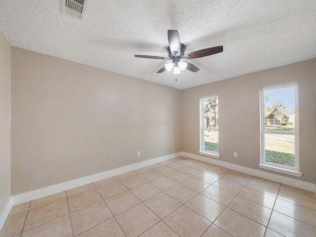 empty room featuring light tile patterned floors, a textured ceiling, and ceiling fan