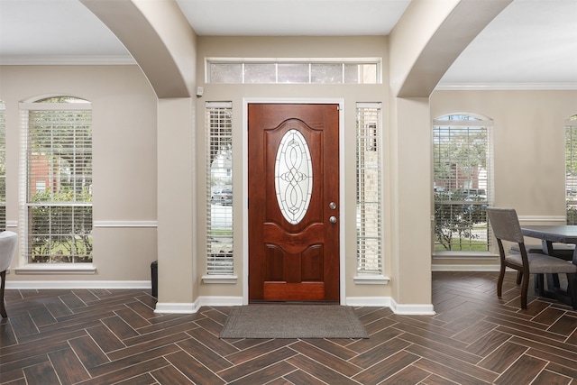 entryway with plenty of natural light, dark parquet flooring, and crown molding