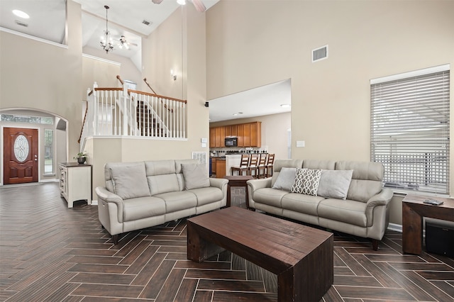 living room featuring dark parquet floors, high vaulted ceiling, and an inviting chandelier