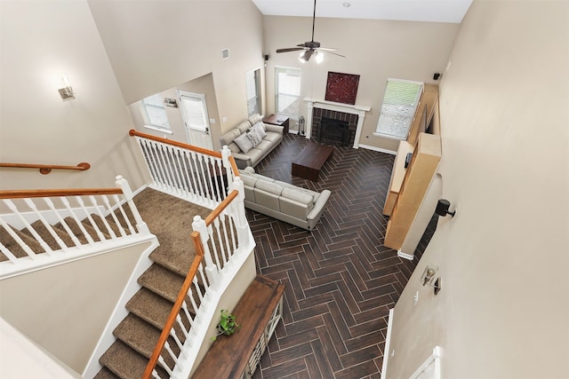 stairway with parquet flooring, a brick fireplace, high vaulted ceiling, and ceiling fan