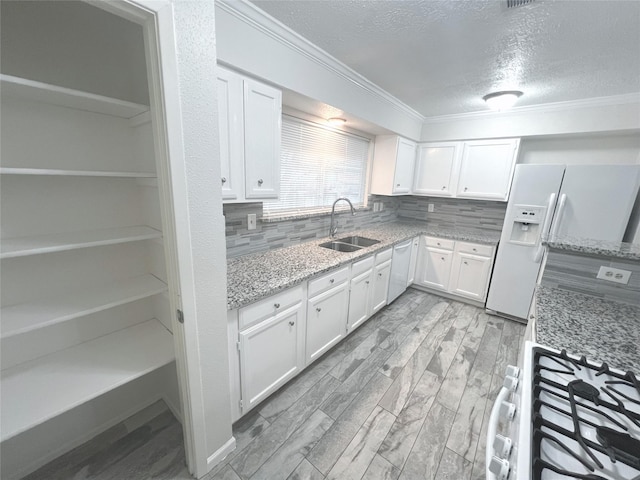 kitchen featuring backsplash, light stone counters, white appliances, sink, and white cabinets