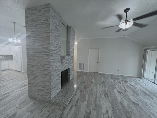 unfurnished living room featuring a tile fireplace, ceiling fan with notable chandelier, light hardwood / wood-style flooring, lofted ceiling, and tile walls