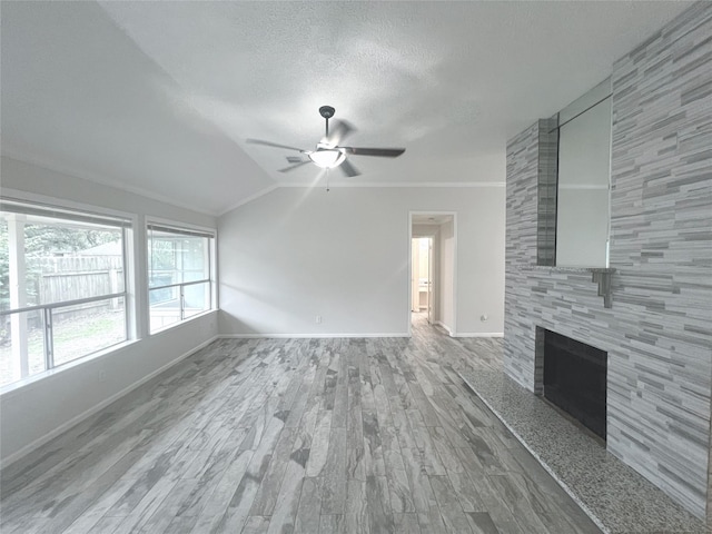 unfurnished living room with a tile fireplace, crown molding, and ceiling fan