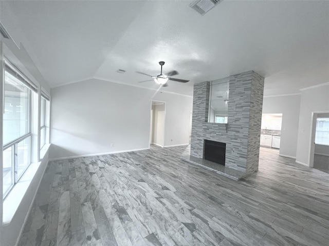 unfurnished living room with hardwood / wood-style floors, a tile fireplace, vaulted ceiling, ceiling fan, and a textured ceiling