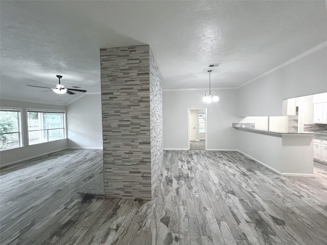 unfurnished living room with a textured ceiling, hardwood / wood-style floors, ceiling fan with notable chandelier, and ornamental molding