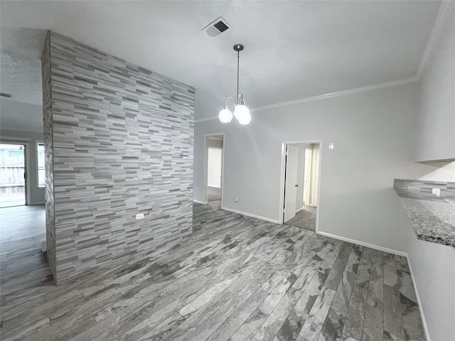 unfurnished dining area featuring hardwood / wood-style floors, a notable chandelier, crown molding, and tile walls