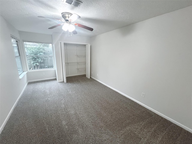 unfurnished bedroom with ceiling fan, a closet, dark carpet, and a textured ceiling