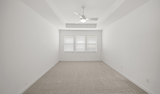 unfurnished room featuring a tray ceiling, ceiling fan, and light colored carpet