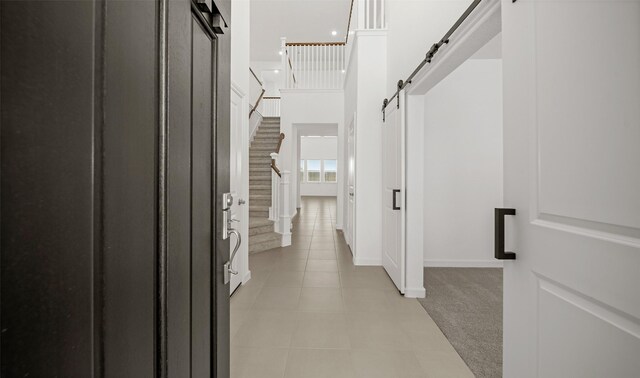 hall with light tile patterned floors and a barn door