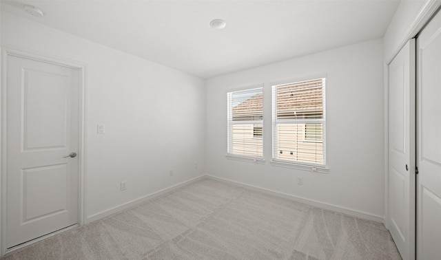 unfurnished bedroom featuring light colored carpet and a closet