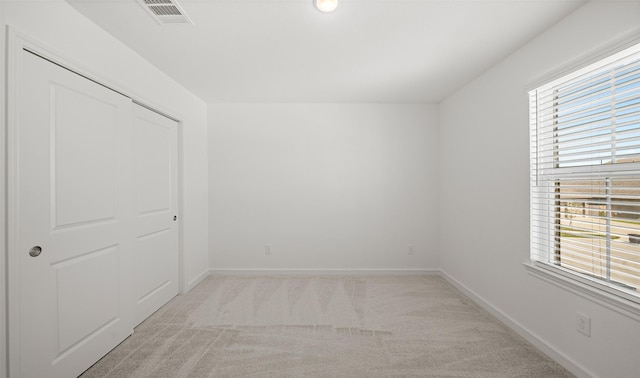 unfurnished bedroom with light carpet, a closet, and multiple windows