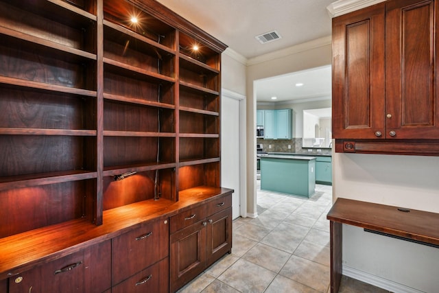 mudroom with crown molding and light tile patterned floors