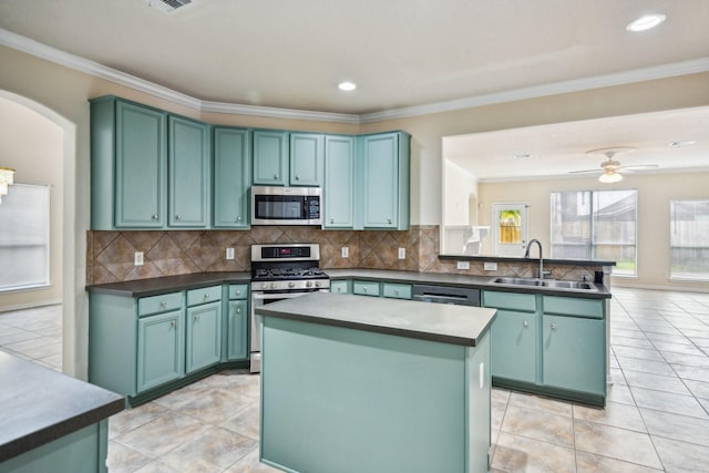 kitchen with light tile patterned flooring, sink, green cabinetry, appliances with stainless steel finishes, and a kitchen island