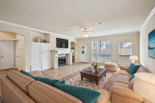 tiled living room with crown molding, a fireplace, and ceiling fan