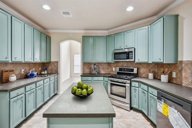 kitchen with sink, stainless steel appliances, tasteful backsplash, ornamental molding, and light tile patterned flooring