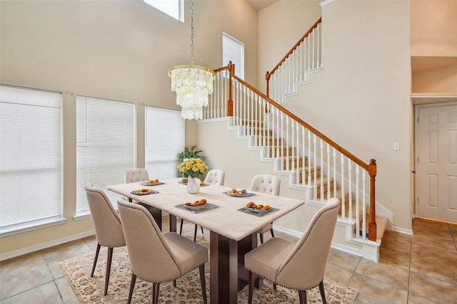 tiled dining area with a high ceiling and an inviting chandelier