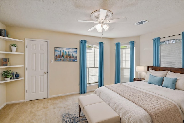 carpeted bedroom with ceiling fan and a textured ceiling