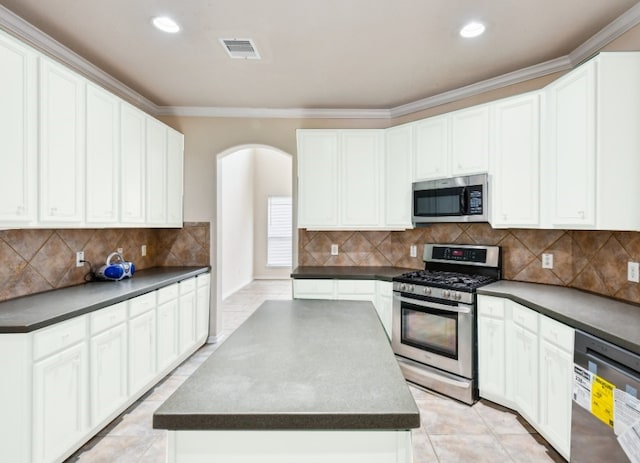 kitchen with backsplash, stainless steel appliances, white cabinets, and a kitchen island