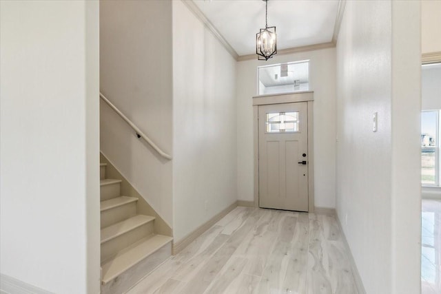 foyer entrance featuring a chandelier, light wood-type flooring, plenty of natural light, and ornamental molding