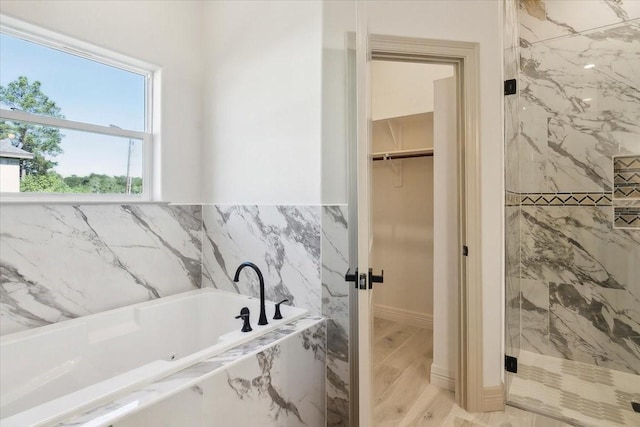 bathroom featuring wood-type flooring and shower with separate bathtub