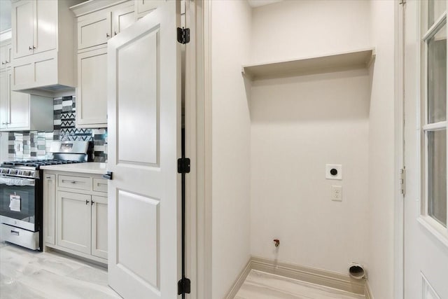 kitchen with tasteful backsplash, white cabinets, custom range hood, and stainless steel gas range