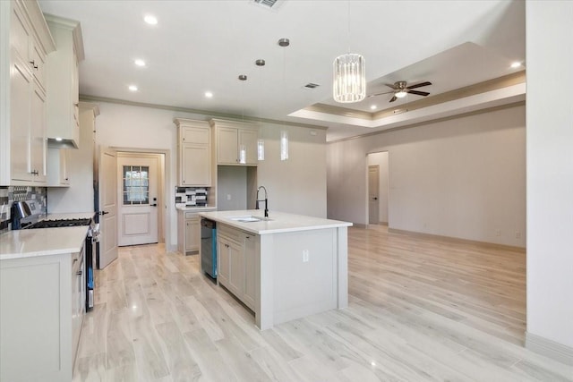 kitchen with tasteful backsplash, stainless steel appliances, a kitchen island with sink, sink, and hanging light fixtures