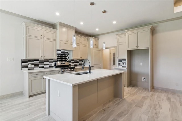 kitchen featuring sink, stainless steel gas range, light hardwood / wood-style flooring, an island with sink, and decorative light fixtures