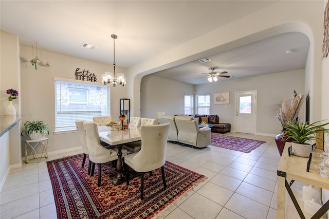 tiled dining area with ceiling fan with notable chandelier