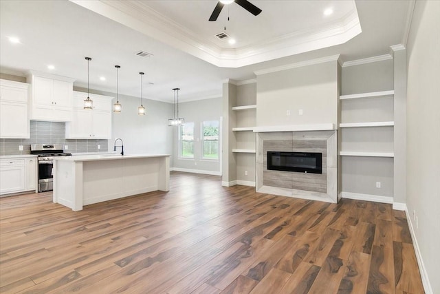 kitchen with white cabinets, wood-type flooring, an island with sink, and stainless steel range