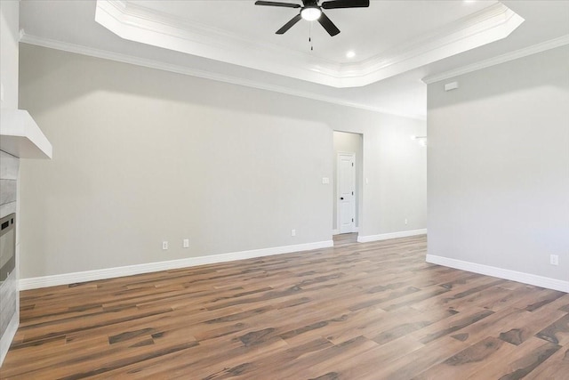 unfurnished living room with a raised ceiling, hardwood / wood-style floors, and ornamental molding