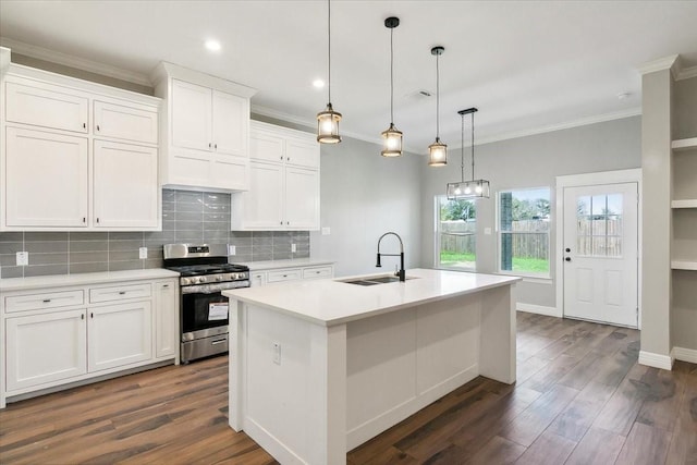 kitchen featuring white cabinetry, stainless steel range, sink, decorative light fixtures, and a kitchen island with sink