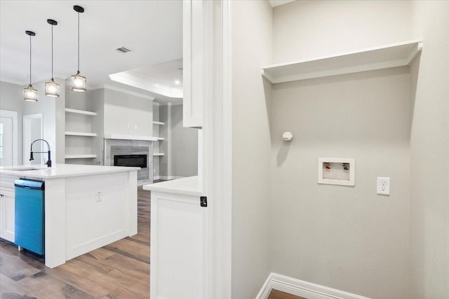 kitchen featuring sink, decorative light fixtures, hardwood / wood-style flooring, dishwashing machine, and white cabinetry