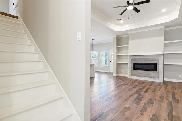 unfurnished living room with hardwood / wood-style flooring, a raised ceiling, ceiling fan, and crown molding