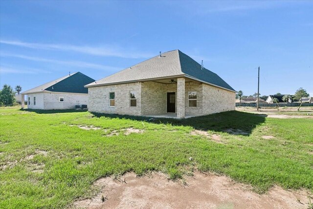 rear view of house featuring a yard and ceiling fan