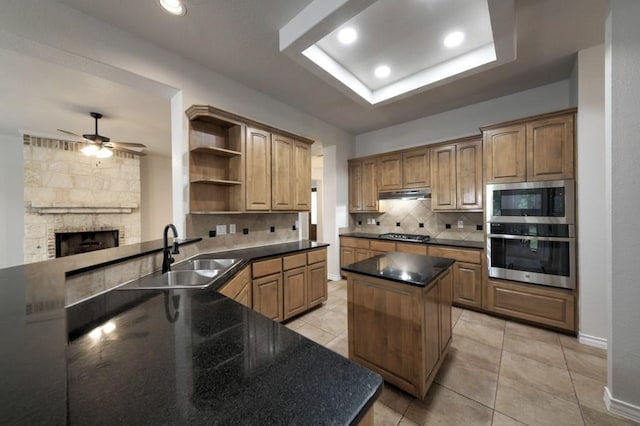 kitchen with tasteful backsplash, a kitchen island, a raised ceiling, sink, and stainless steel appliances