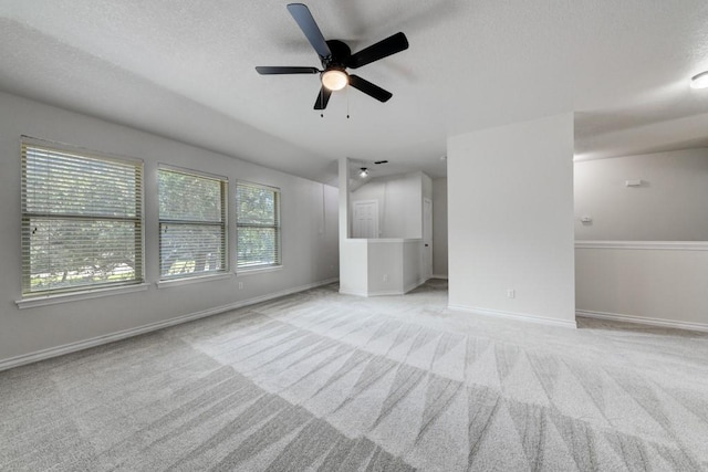 unfurnished living room featuring ceiling fan, light colored carpet, a textured ceiling, and lofted ceiling