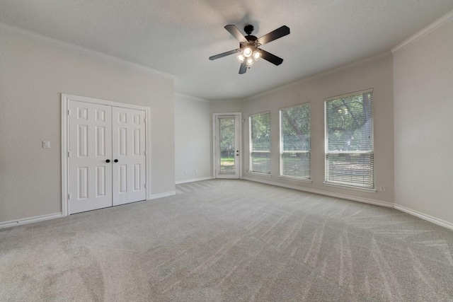 spare room featuring ceiling fan, light colored carpet, and ornamental molding