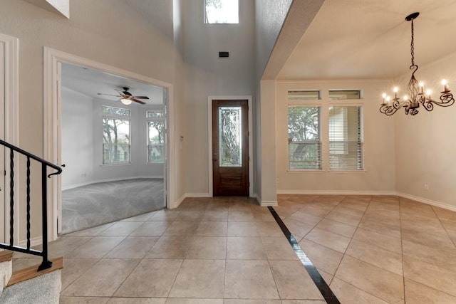 foyer entrance featuring light tile patterned flooring, ceiling fan with notable chandelier, and plenty of natural light