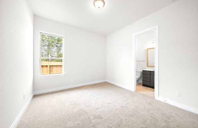 unfurnished bedroom featuring light colored carpet and connected bathroom