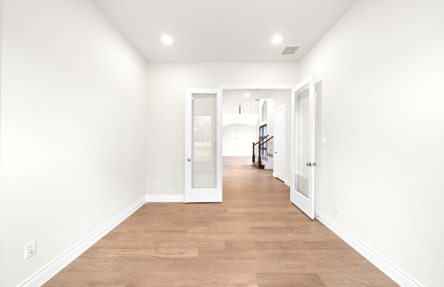 corridor with french doors and light hardwood / wood-style flooring