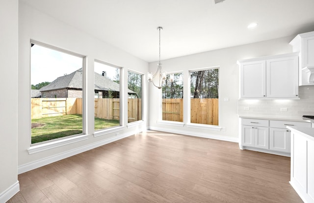 unfurnished dining area featuring light wood-type flooring and an inviting chandelier