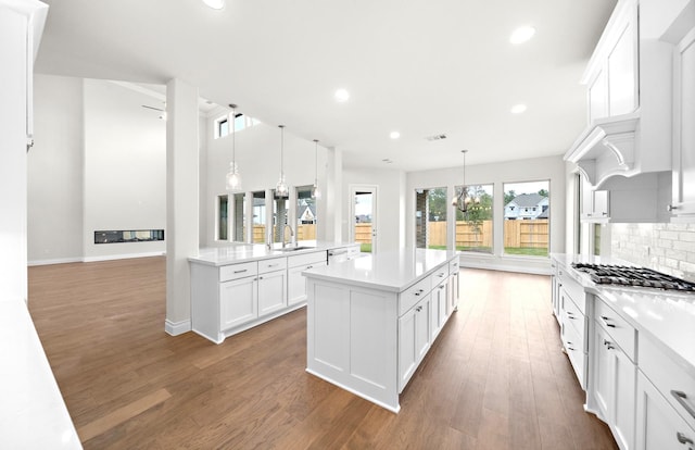 kitchen with white cabinets, hanging light fixtures, appliances with stainless steel finishes, and dark wood-type flooring