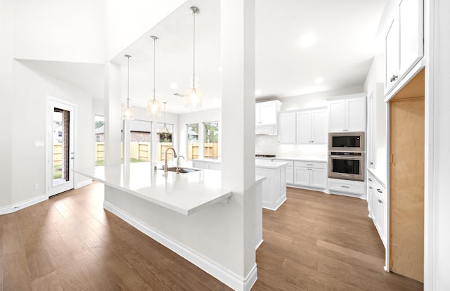 kitchen with white cabinets, a healthy amount of sunlight, a center island with sink, and appliances with stainless steel finishes