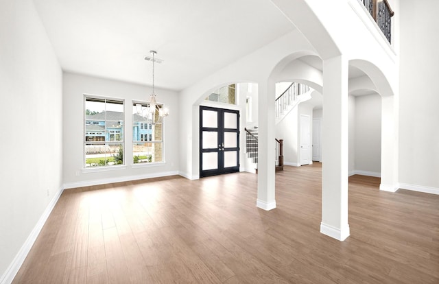 unfurnished room featuring wood-type flooring, french doors, and an inviting chandelier