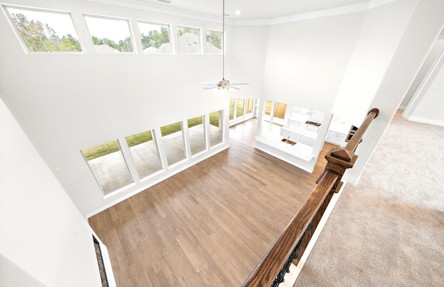 staircase featuring hardwood / wood-style floors, ceiling fan, and crown molding