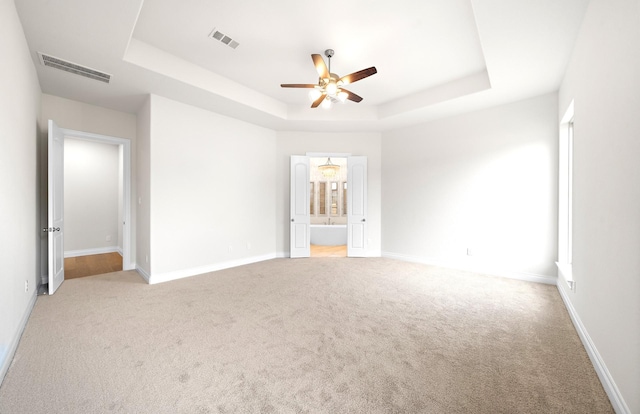 carpeted spare room with ceiling fan and a raised ceiling