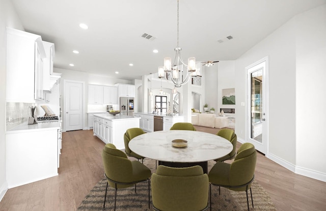 dining area with wood-type flooring and ceiling fan with notable chandelier