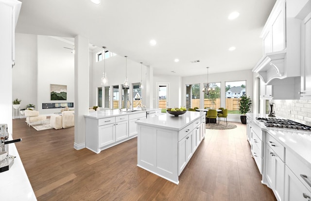 kitchen with a kitchen island, dark hardwood / wood-style flooring, backsplash, decorative light fixtures, and white cabinets